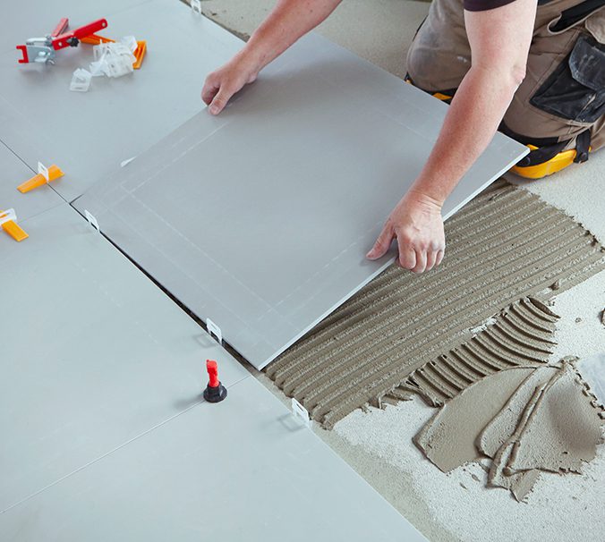 A person laying tile on the floor